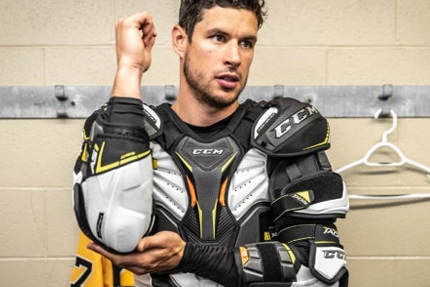 Hockey player wearing protective gear in locker room.