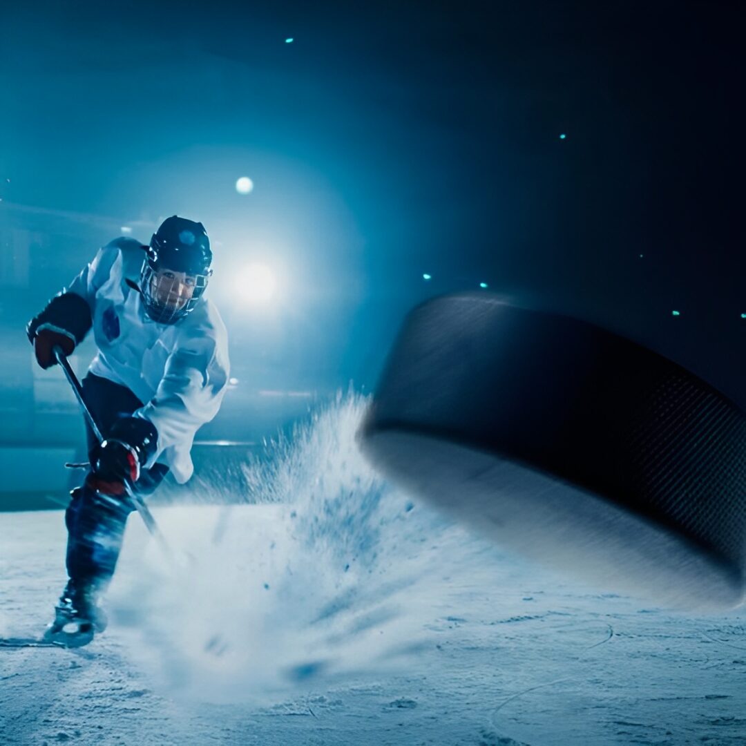 Hockey player shooting puck on ice rink.